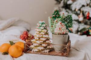 jul sötsaker, pepparkaka målad med glasyr, klubbor och maränger i de form av jul träd och mandariner på en skön bricka. hemlagad kakor. utsökt mat för de vinter- högtider foto