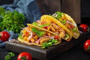 mexikansk tacos med majs tortilla. tortilla med kyckling kött, majs, sallad och lök foto