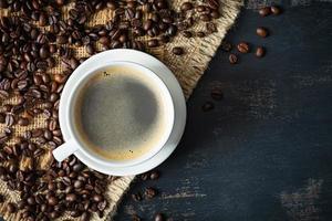 kopp av kaffe med kaffe bönor på mörk bakgrund. råna av varm dryck kaffe foto