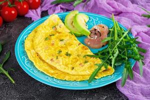 friterad omelett med skinka, lök och örter. frukost med krypterade ägg foto