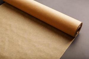 en rulla av utvecklas brun pergament papper, för bakning mat i på en mörk bakgrund, topp se. foto