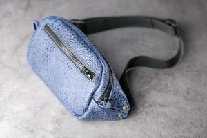midja väska tillverkad av blå läder, banan på en grå bakgrund. foto