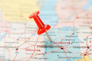 röd prästerlig nål på en Karta av usa, indiana och de huvudstad Indianapolis. stänga upp Karta av sida skyddade med i väntan på ändringar indiana med röd kryssa foto