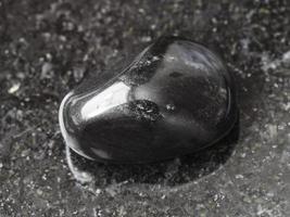 polerad svart obsidian pärla sten på mörk foto