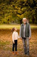 farfar utgifterna tid med hans barnbarn i parkera på höst dag foto