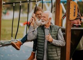 farfar utgifterna tid med hans barnbarn i parkera lekplats på höst dag foto