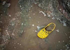 mycket smutsig gul sko på de Strand av en salt sjö på en solig dag. foto