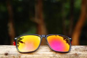 färgrik solglasögon med reflexion av träd på en trä- pinne. foto