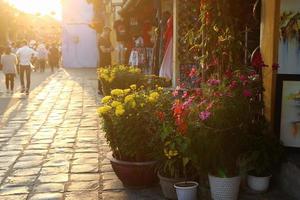 hoi en, vietnam - februari 17, 2018. turistiska gata i gammal historisk stad med butiker, färgrik blommor och gående turister på de solnedgång. foto