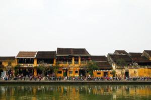 hoi en, vietnam - februari 12, 2018. de vägbank av tor bon flod med gul byggnader och traditionell trä- båtar. de historisk gammal stad av hoi ett är unesco värld arv webbplats. foto