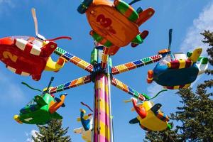 barns karuseller helikoptrar i ett nöje parkera, karuseller och människor under de sommar i de stad foto