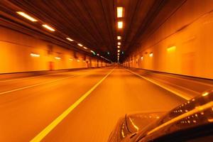 körning en bil genom en tunnel belyst förbi lampor körning en bil på natt genom de stad, reser foto