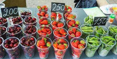 koppar med bär för försäljning i de parkera, körsbär, ärtor, jordgubbar, de pris av bär, gata handel i sommar foto