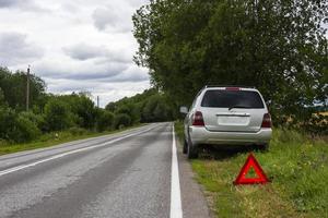 en bil väntar för reparera efter en bryta ner, en bruten bil på de sida av de väg, ett nödsituation sluta tecken foto