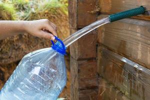 samlar naturlig vår vatten i en 5-liter plast flaska, fyllning de flaska med färsk rena dricka vatten foto