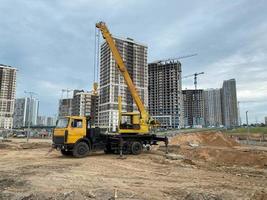 stor gul rörlighet modern industriell konstruktion kran monterad på en lastbil är Begagnade i de konstruktion av ny hus, hus, byggnader i en stor stad foto