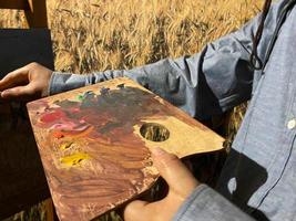 konstnär borsta blanda Färg olja målning på palett är innehav i hans hand närbild foto