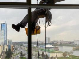 industriell bergsbestigning, en man tvättar de fönster av en höghus byggnad foto