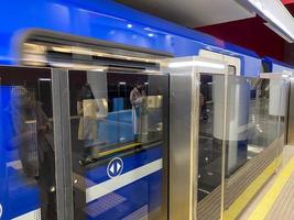 en blå tåg transport med öppen och stängd glidning mekanisk dörr på en tåg station plattform foto