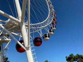 närbild modern ferris hjul mot blå himmel och vit moln. ferris hjul på tivoli för underhållning och rekreation på Semester. modern konstruktion av ferris hjul i nöje. roligt festival foto