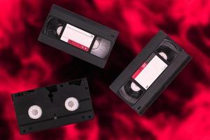 tre video kassetter, vhs, kompis secam, röd och svart suddig retro bakgrund. foto