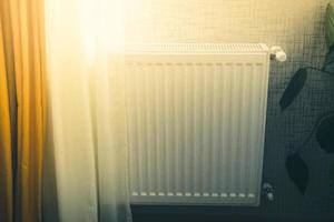 vit radiator med temperatur kontrollera ventil central uppvärmning i modern byggnader förbi fönster. foto