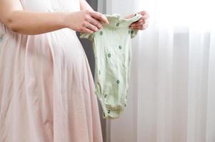 gravid kvinna framställning kläder för henne baby.packning bebis kläder, förbereder för födelse foto
