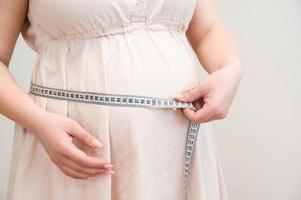 sida se på en gravid kvinna mätning henne mage. foto