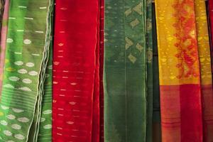 bangladeshiska kvinnor, s traditionell färgrik jamdani saree hängande i de detaljhandeln utställningslokaler. färgrik jamdani saree textur bakgrund foto