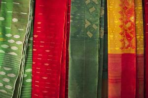 bangladeshiska kvinnor, s traditionell färgrik jamdani saree hängande i de detaljhandeln utställningslokaler. färgrik jamdani saree textur bakgrund foto