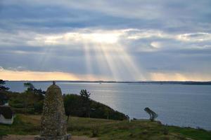 på de kust av hundested. Sol strålar ha sönder genom de dramatisk himmel genom de moln foto