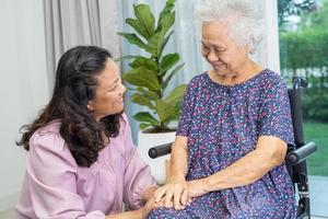 vårdgivare hjälp och vård asiatisk senior eller äldre gammal lady kvinna patient Sammanträde på rullstol på Hem. foto