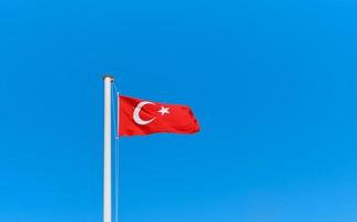 turkiska flagga på en flaggstång mot en klar blå himmel med kopia Plats. aning för bakgrund eller tapet foto