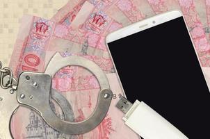 10 ukrainska hryvnias räkningar och smartphone med polis handklovar. begrepp av hackare nätfiske attacker, olaglig lurendrejeri eller skadliga program mjuk distribution foto
