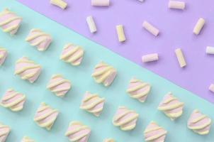 färgrik marshmallow lagd ut på violett och blå papper bakgrund. pastell kreativ texturerad mönster. minimal foto