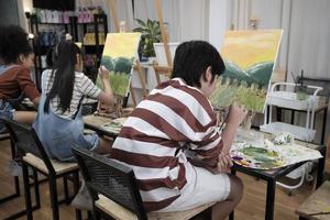 en grupp av studerande barn koncentrat på akryl Färg bild målning med en paintbrush på duk i konst klassrum, kreativt inlärning med talanger och Kompetens på elementärt skola studio utbildning. foto