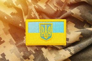 militär kamouflage tyg med ukrainska flagga på enhetlig sparre foto