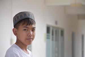 porträtt ung sydöst asiatisk islamic eller muslim pojke i vit skjorta och hatt, isolerat på vit, mjuk och selektiv fokus. foto
