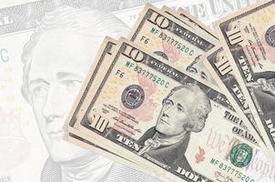 10 oss dollar räkningar lögner i stack på bakgrund av stor halvtransparent sedel. abstrakt presentation av nationell valuta foto