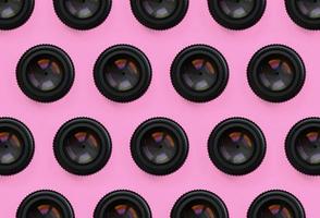 en få kamera linser med en stängd öppning lögn på textur bakgrund av mode pastell rosa Färg papper i minimal begrepp. abstrakt trendig mönster foto