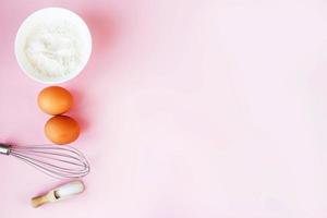 Ingredienser för matlagning bakning - mjöl, ägg, socker, rullande stift på rosa bakgrund. begrepp av matlagning efterrätt. foto