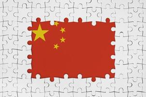 Kina flagga i ram av vit pussel bitar med saknas central del foto