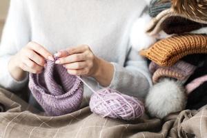 stänga upp kvinna händer stickning handgjort hatt kvinna stickat ull- kläder stickning nålar närbild naturlig ull fritid aktivitet Hem hobby foto