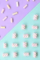 färgrik marshmallow lagd ut på violett och blå papper bakgrund. pastell kreativ texturerad mönster. minimal foto