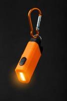 orange led ficklampa med en karbinhake på en svart bakgrund. led lampor i flyg. foto