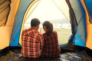 tält sorglös par avkopplande avlägsen resa begrepp - par av ung backpackers Sammanträde i en tält ser på bok och planera deras Nästa camping äventyr foto