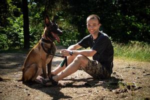 ung caucasian hipster spenderar tid med hans hund i de parkera på en solig sommar dag. de begrepp av en sällskapsdjur som en familj medlem foto