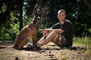 ung caucasian hipster spenderar tid med hans hund i de parkera på en solig sommar dag. de begrepp av en sällskapsdjur som en familj medlem foto