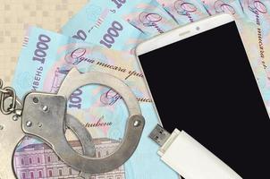1000 ukrainska hryvnias räkningar och smartphone med polis handklovar. begrepp av hackare nätfiske attacker, olaglig lurendrejeri eller skadliga program mjuk distribution foto