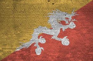 bhutan flagga avbildad i måla färger på gammal tegel vägg. texturerad baner på stor tegel vägg murverk bakgrund foto